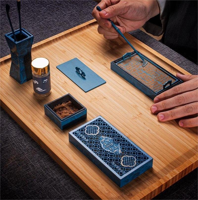 Hands working with a blue rectangular incense-seal set